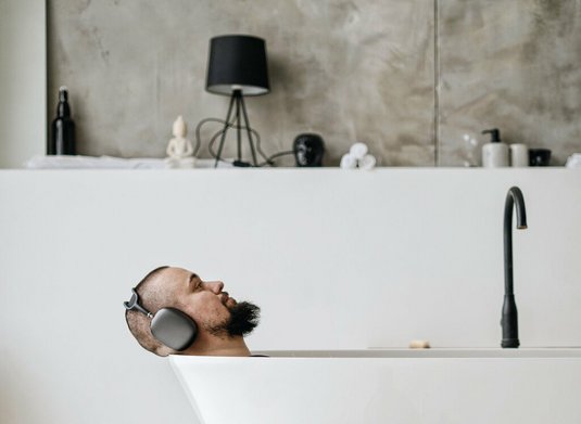 Mann entspannt mit Musik in der Badewanne