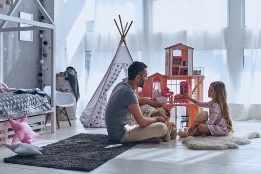Vater und Tochter spielen gemeinsam mit dem Puppenhaus